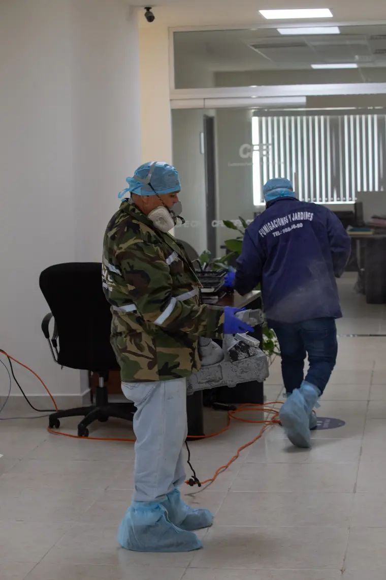 Técnico de Rodica con equipo de protección completo trabajando en una oficina